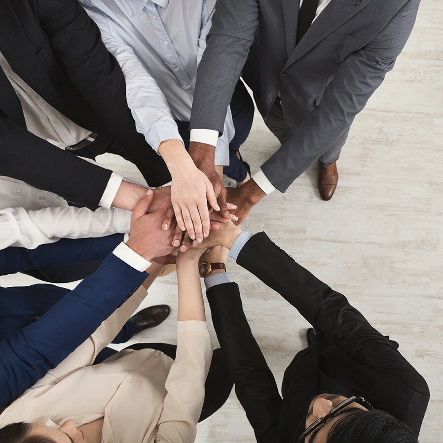 United coworkers standing with their hands together in modern office, celebrating victory, top view, teambuilding and unity , copy space